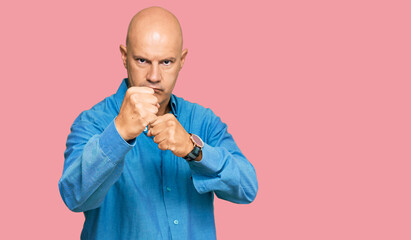 Middle age bald man wearing casual clothes ready to fight with fist defense gesture, angry and upset face, afraid of problem