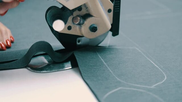 Woman cuts dark fabric with a roller cutting knife