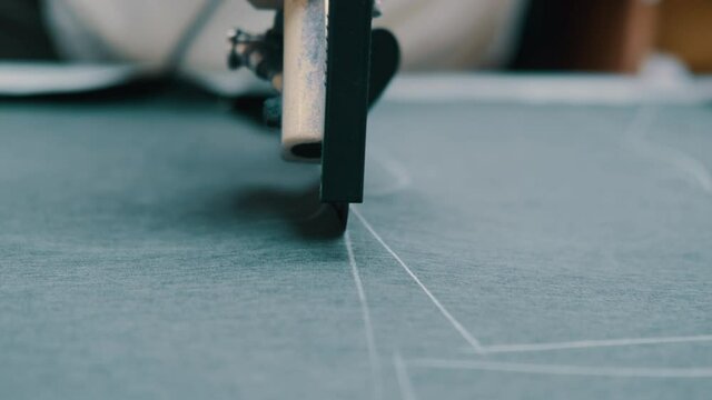 Woman cuts dark fabric with a roller cutting knife