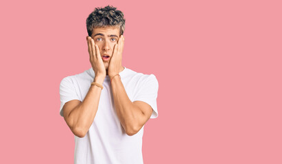 Young handsome man wearing casual white tshirt afraid and shocked, surprise and amazed expression...