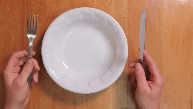 Sitting with an empty plate at the table, waiting for food impatiently