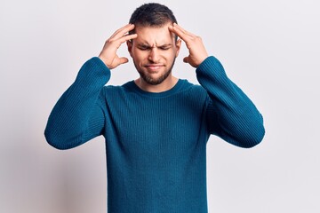 Young handsome man wearing casual sweater with hand on head, headache because stress. suffering migraine.
