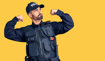 Fototapeta premium Young hispanic man wearing police uniform showing arms muscles smiling proud. fitness concept.