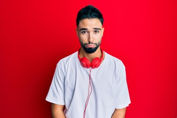 Young man with beard listening to music using headphones depressed and worry for distress, crying angry and afraid. sad expression.