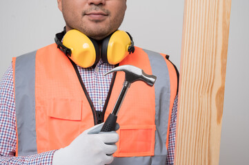 Close up craftsman holding wood and hammer standing in studio white background. Carpenter in safety uniform go to working..