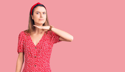Young beautiful girl wearing dress and diadem cutting throat with hand as knife, threaten aggression with furious violence