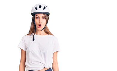 Young beautiful girl wearing bike helmet scared and amazed with open mouth for surprise, disbelief face