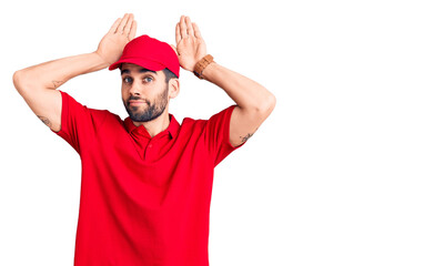 Naklejka premium Young handsome man with beard wearing delivery uniform doing bunny ears gesture with hands palms looking cynical and skeptical. easter rabbit concept.