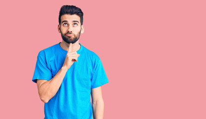 Fototapeta premium Young handsome man with beard wearing casual t-shirt thinking concentrated about doubt with finger on chin and looking up wondering
