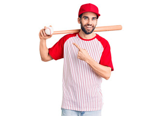 Young handsome man with beard playing baseball holding bat and ball smiling happy pointing with hand and finger