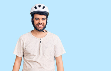 Young hispanic man wearing bike helmet looking positive and happy standing and smiling with a confident smile showing teeth
