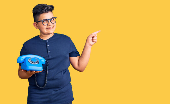 Little boy kid using vintage telephone smiling happy pointing with hand and finger to the side
