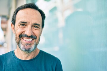 Obraz premium Middle age man with beard smiling happy outdoors leaning on the wall