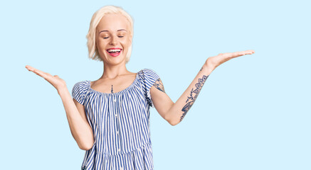 Young blonde woman with tattoo wearing casual clothes celebrating mad and crazy for success with arms raised and closed eyes screaming excited. winner concept