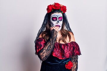 Young woman wearing day of the dead costume over white looking stressed and nervous with hands on mouth biting nails. anxiety problem.