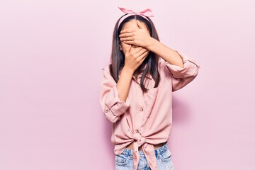 Beautiful child girl wearing casual clothes covering eyes and mouth with hands, surprised and shocked. hiding emotion