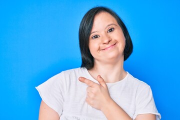 Brunette woman with down syndrome wearing casual clothes smiling cheerful pointing with hand and finger up to the side