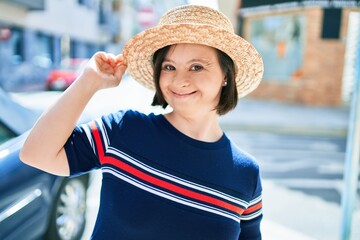 Beautiful brunette woman with down syndrome wearing a summer hat at the town on a sunny day