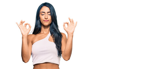 Fototapeta na wymiar Beautiful hispanic woman wearing casual clothes relaxed and smiling with eyes closed doing meditation gesture with fingers. yoga concept.