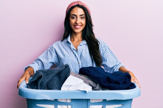 Beautiful hispanic woman holding laundry basket smiling with a happy and cool smile on face. showing teeth.