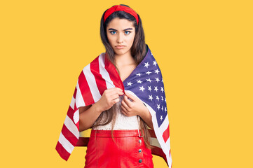 Brunette teenager girl holding united states flag thinking attitude and sober expression looking self confident