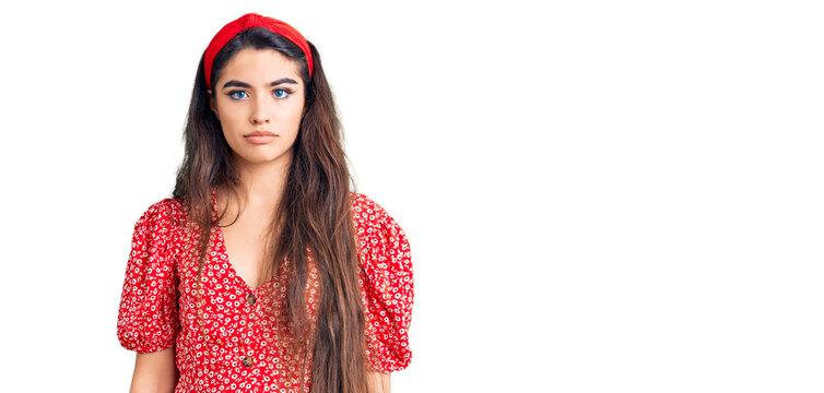 Brunette teenager girl wearing summer dress relaxed with serious expression on face. simple and natural looking at the camera.
