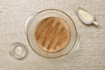 The stage of preparing a batch of yeast dough. Dissolving yeast in a transparent deep bowl with milk.