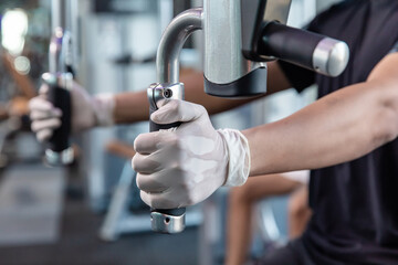 Asia men working out wearing surgical mask & latex rubber gloves, COVID-19 pandemic social distancing rules while working out in  a gym, new normal & social distancing concept
