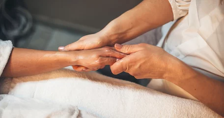 Canvas schilderij Nagelstudio Caucasian spa worker massaging client's hand with special lotion during a hand massage session at spa salon  © Strelciuc