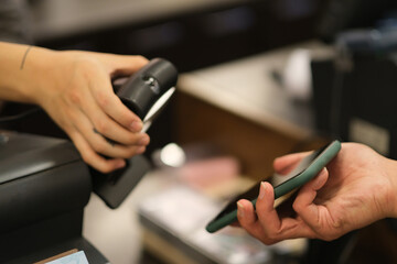 close up hand holding mobile phone to scan to pay in coffee shop. soft focus