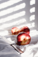 peaches on white cloth with American window light with a knife on sunny white background