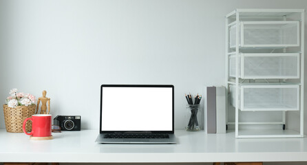 Minimal work space with mock up computer with white screen, coffee cup and office supplies on white table.