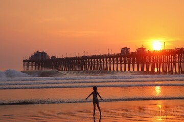 Girl playing by the Oceanside Pier at sunset