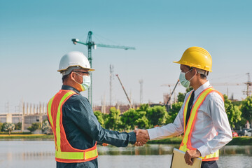 Two Engineer shake hand on site construction, People wearing face mask