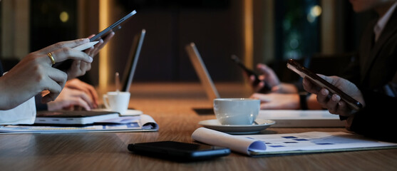 Cropped shot of business people using smart phone and laptop in meeting room.
