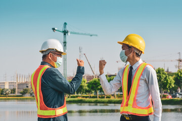 Construction engineer shake hand no touching on building construction site, Worker Man wearing face mask