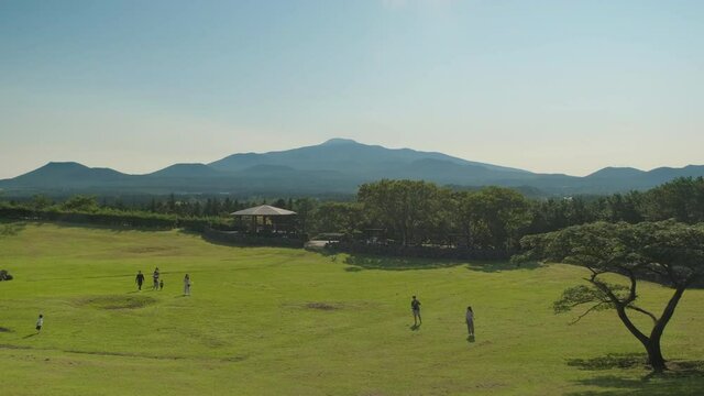 A family taking a walk in a vast field overlooking Mt. Halla. Halla Mountain.