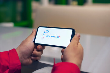 The guy holds a smartphone with a new message alert on the smartphone screen.