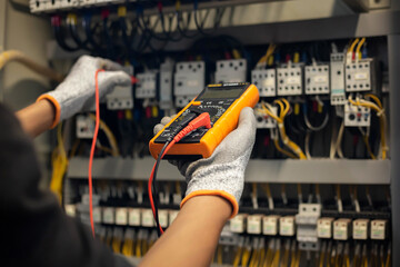 Electrician engineer uses a multimeter to test the electrical installation and power line current...