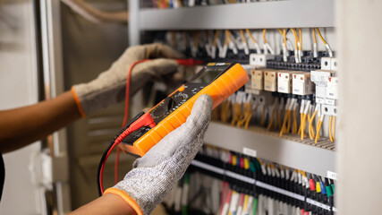 Electrician engineer uses a multimeter to test the electrical installation and power line current...