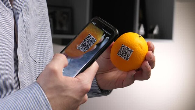 Scanning an orange with a QR code using a smartphone device.