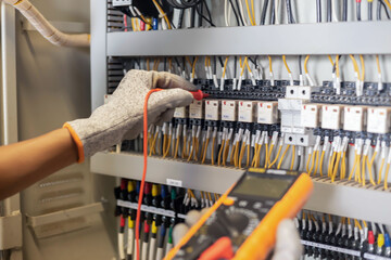 Electrician engineer uses a multimeter to test the electrical installation and power line current...