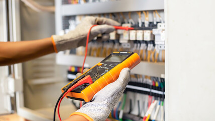 Electrician engineer uses a multimeter to test the electrical installation and power line current...
