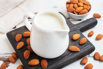 Almond milk in ceramic milk jug on a gray background. Copy space.
