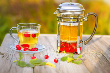  A cup of hot rosehip tea on a wooden table in the autumn garden. 