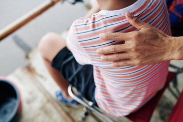 Close-up image of father patting his son on shoulder to support him at his firsh fishing