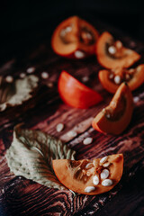 orange cut pumpkins and a towel on a wooden texture table. white pumpkin seeds in pumpkin pulp. orange ripe pumpkin on a textured light table. autumn still life with pumpkin on a light kitchen table
