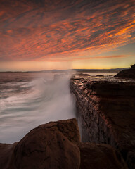 Long exposure photo of a rock wall hit by large waves, Australia