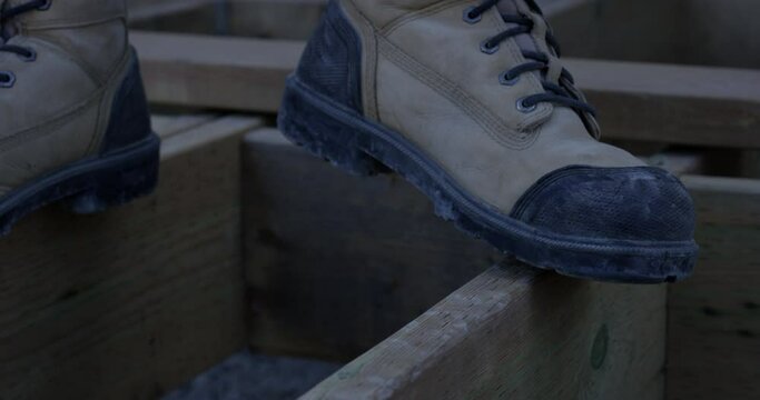 Construction worker standing between two joists - close up on safety bootes
