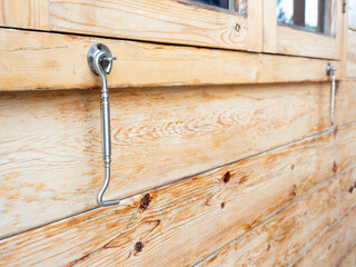 Old-fashioned window latch hook hanging on wood wall background.